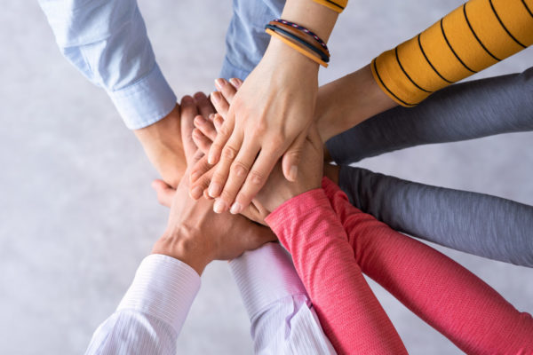 Close up top view of young business people putting their hands together. Stack of hands. Unity and teamwork concept.